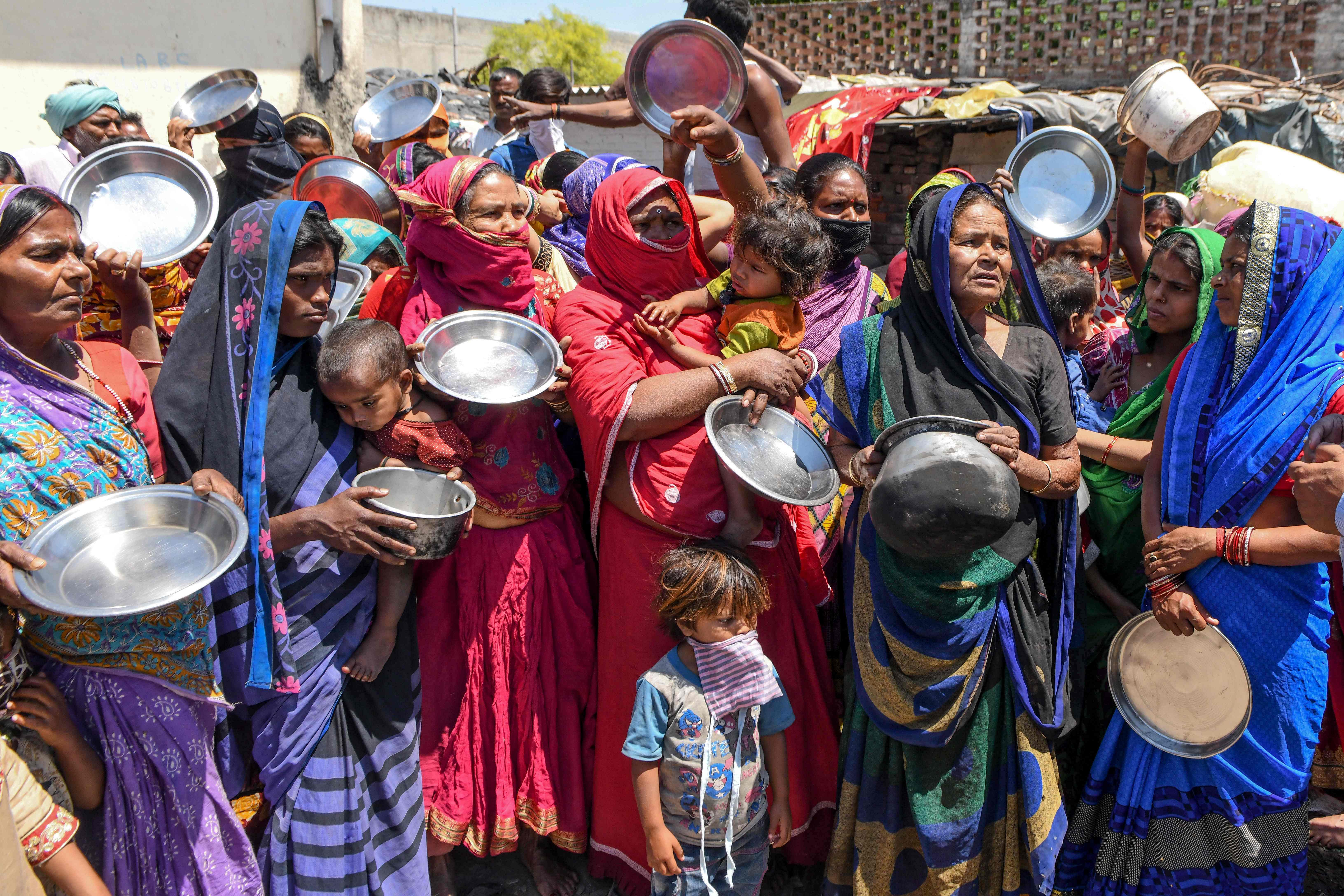 Migrant labourers and families from Bihar and Uttar Pradesh states hold kitchen utensils as they protest against the government for the lack of food at a slum area during a government-imposed nationwide lockdown as a preventive measure against the Covid-19, in Amritsar on April 22, 2020. Credit: AFP File Photo