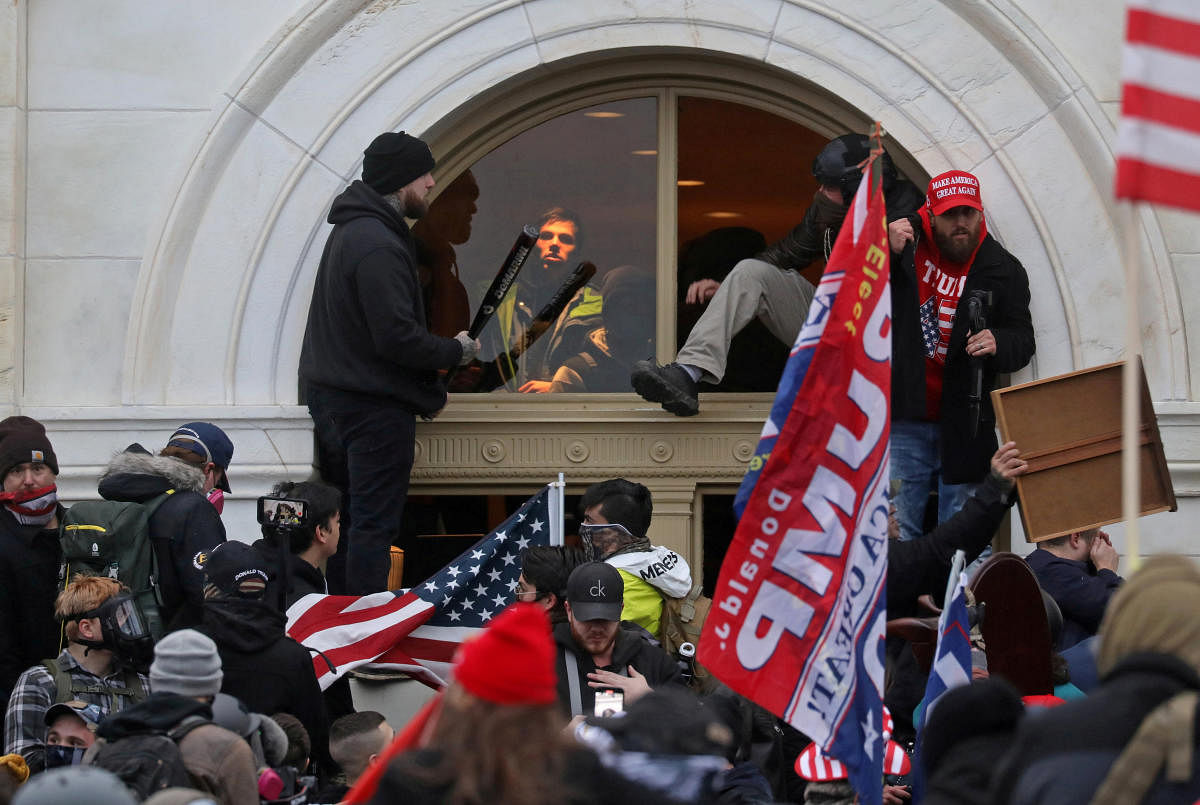 A mob of supporters of U.S. President Donald Trump climb through a window they broke as they storm the U.S. Capitol Building in Washington, U.S., January 6, 2021. Credit: Reuters File Photo