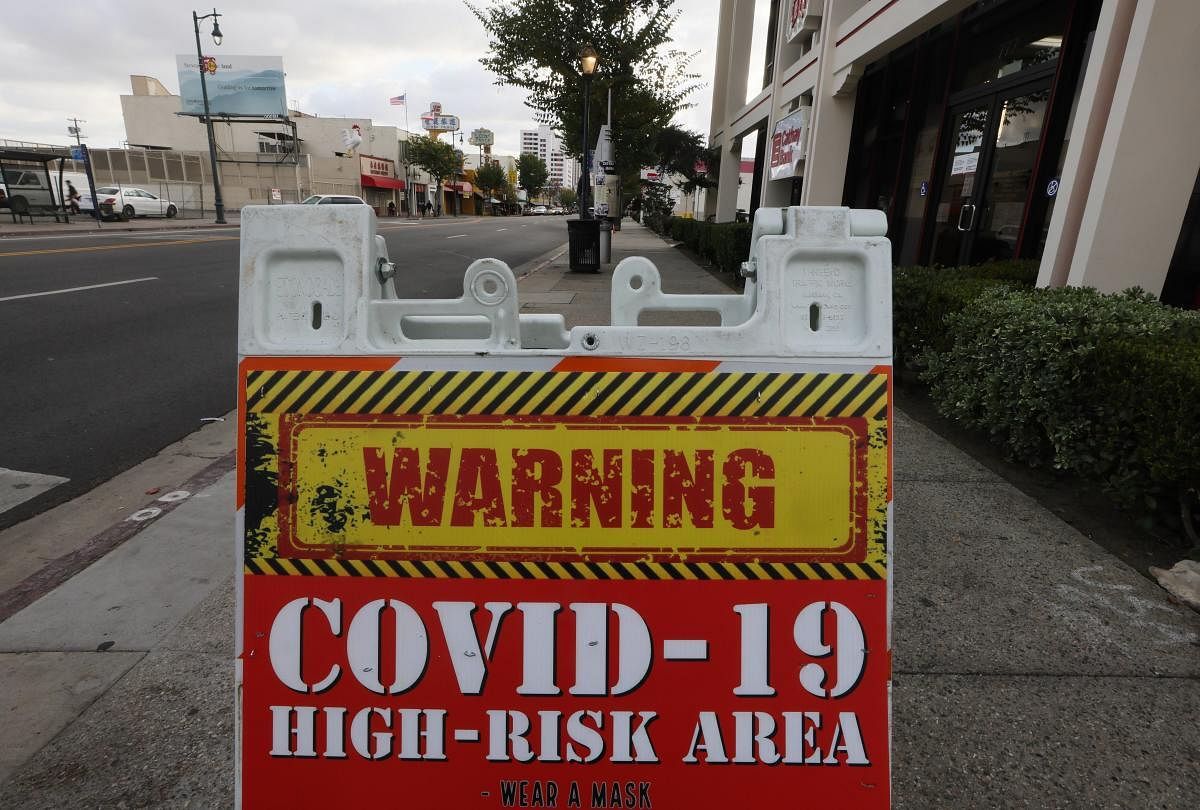 A sign reading 'COVID-19 High-Risk Area' is posted on a downtown sidewalk amid a surge in coronavirus infections on January 22, 2021 in Los Angeles, California. One hundred sidewalk warning signs have been placed in some high-risk areas of the city as mass vaccinations have begun. California has become the first state in the nation to record 3 million known coronavirus infections. Los Angeles County reported more than 250 COVID-19 fatalities on January 22. Credit: Getty Images/AFP