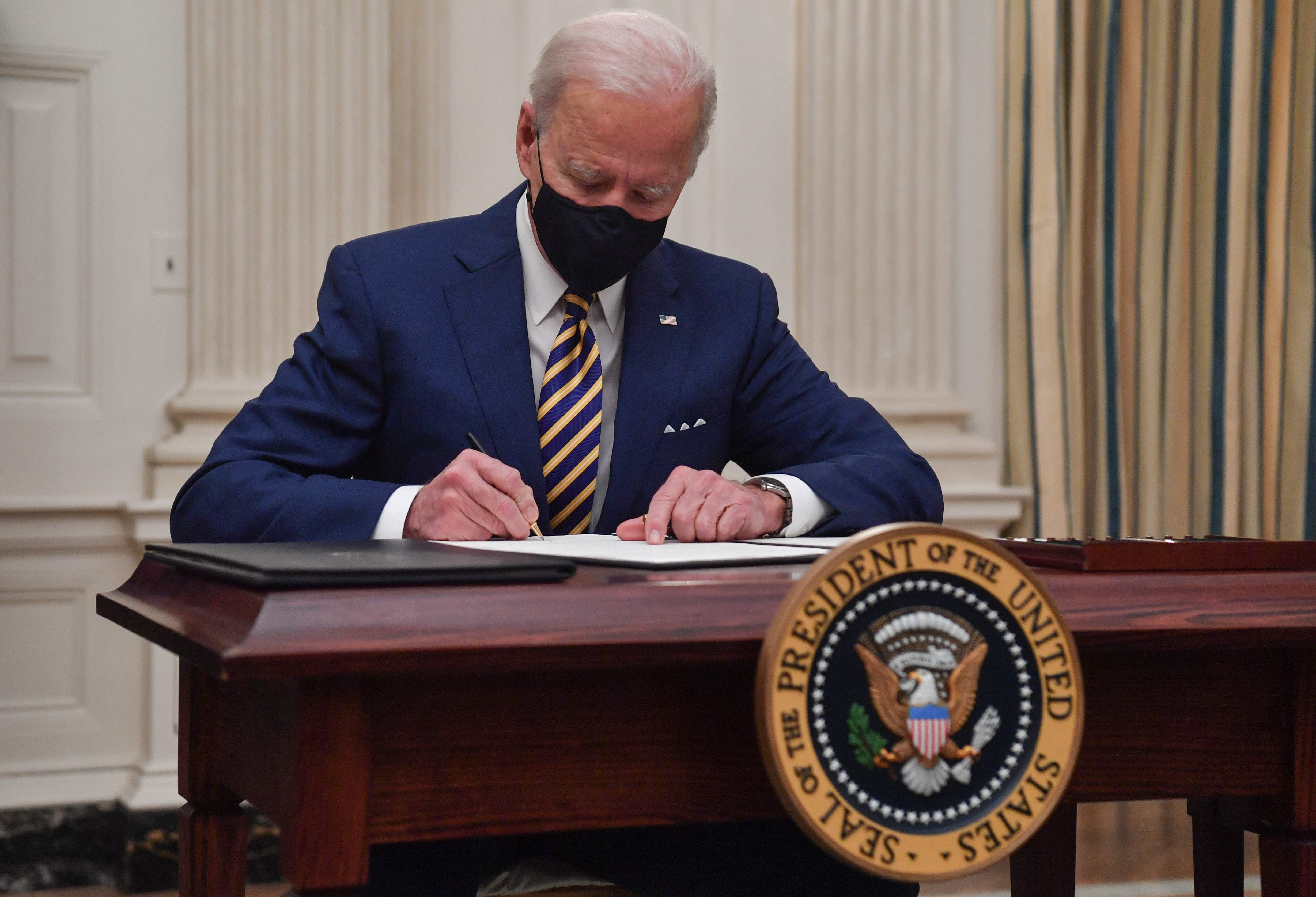S President Joe Biden signs executive orders for economic relief to Covid-hit families and businesses in the State Dining Room of the White House in Washington, DC, on January 22, 2021. Credit: AFP Photo