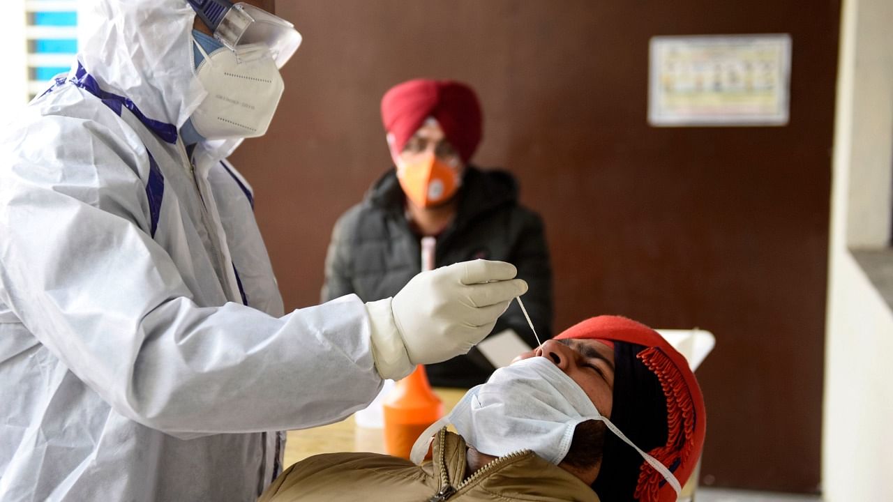 A health worker collects a nasal swab sample from a police personnel to test for the Covid-19 coronavirus, at the Community Health Centre, on the outskirts of Amritsar on January 25, 2021. Credit: AFP Photo