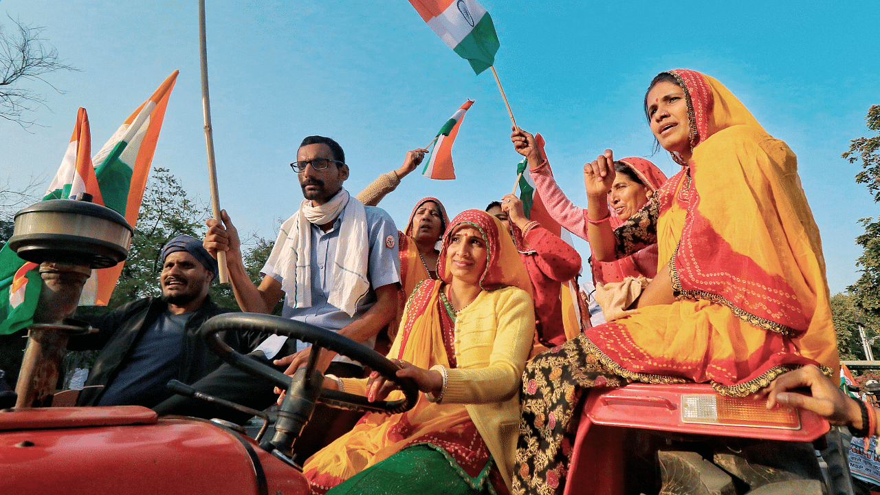 Farmers hold the Tricolor as they ride on a tractor during their protest against Centre's farm reform laws, on the eve of 72nd Republic Day. Credit: PTI Photo