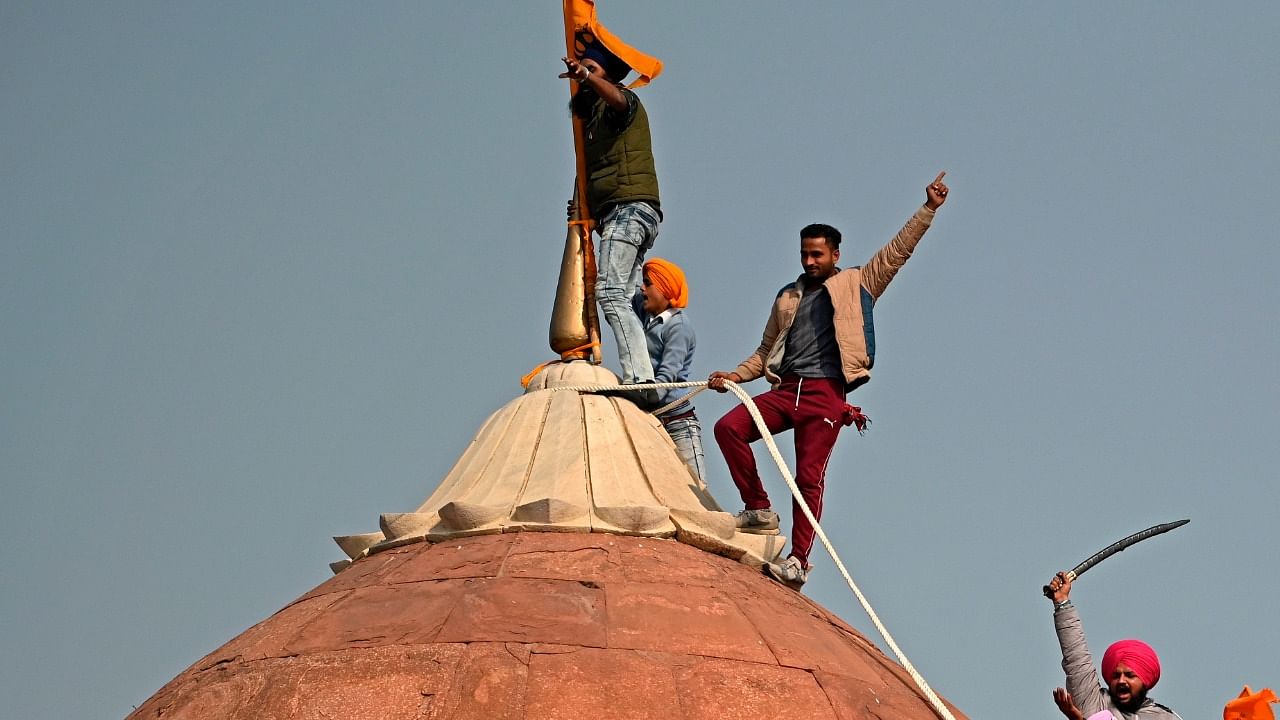 Protesters climb on a dome at the ramparts of the Red Fort as farmers continue to demonstrate against the central government's recent agricultural reforms in New Delhi on January 26, 2021. Credit: AFP Photo
