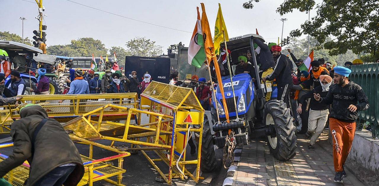  Farmers break a police barricade as they participate in the 'Kisan Gantantra Parade' during their protest against Centre's farm reform laws, on the occasion of 72nd Republic Day, near Red Fort in New Delhi, Tuesday, Jan. 26, 2021. Credit: PTI Photo