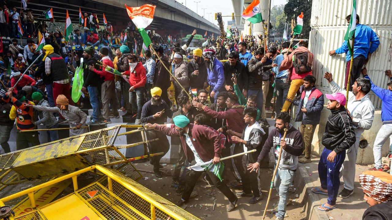 Farmers attempt to break a barricade near Nangloi as they participate in the 'Kisan Gantantra Parade', during their ongoing protest against Centre's farm reform laws, on the occasion of 72nd Republic Day, in New Delhi. Credit: PTI.
