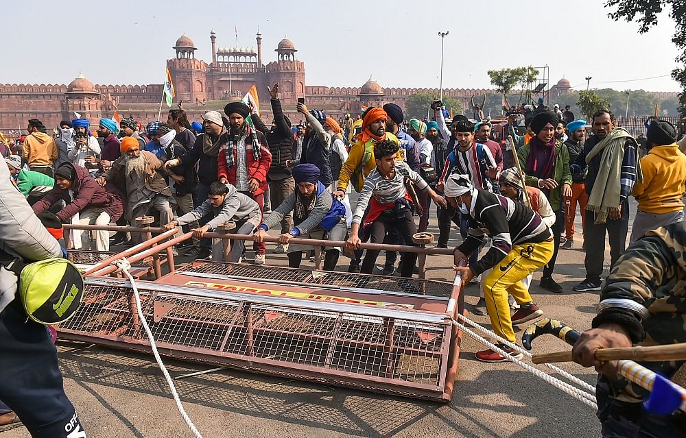 Farmers remove police barricades set up near the Red Fort during the 'Kisan Gantantra Parade' amid the 72nd Republic Day celebrations. Credit: PTI Photo