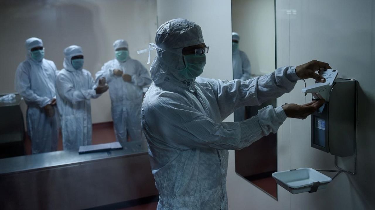 Employees prepare themselves before getting inside a lab where Covishield, AstraZeneca-Oxford's Covid-19 coronavirus vaccine is being manufactured, at India's Serum Institute in Pune. Credit: AFP.