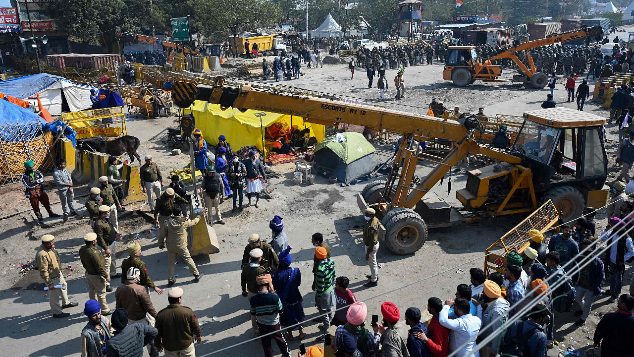 Farmers (R) watch as police (C) set up road blocks at the Delhi-Haryana state border in Singhu. Credit: AFP Photo