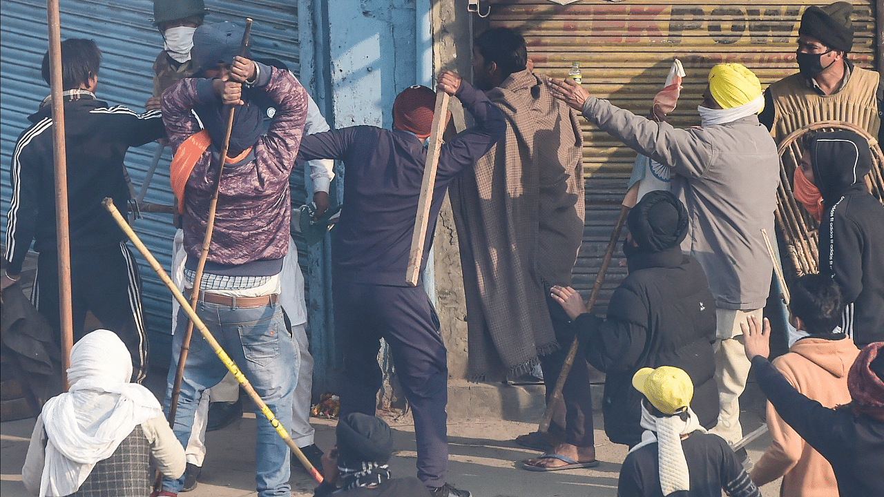 Farmers charge a security person during clashes after their tractor rally turned violent, in New Delhi. Credit: PTI Photo