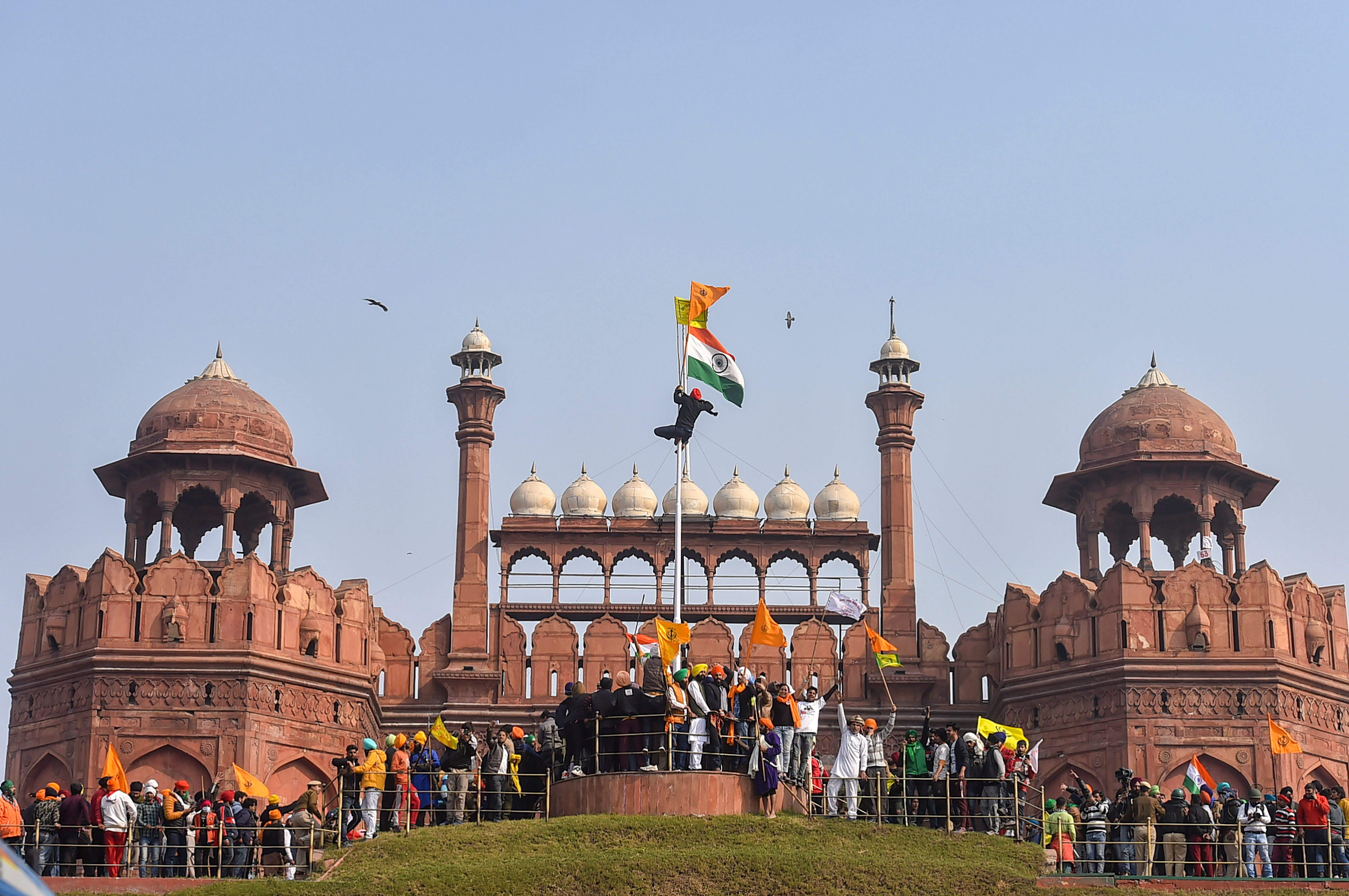 Farmers hoist flags at the Red Fort during the 'tractor rally' amid the 72nd Republic Day celebrations, in New Delhi, Tuesday, Jan. 26, 2021. Credit: PTI Photo