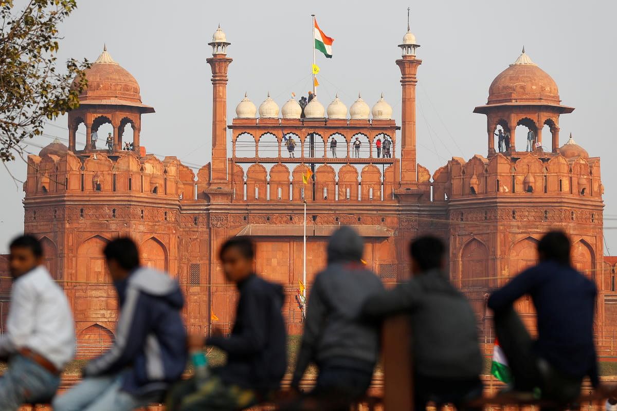 A farmer holds a flag on top of the historic Red Fort, during a protest against farm laws introduced by the government. Credit: Reuters photo. 
