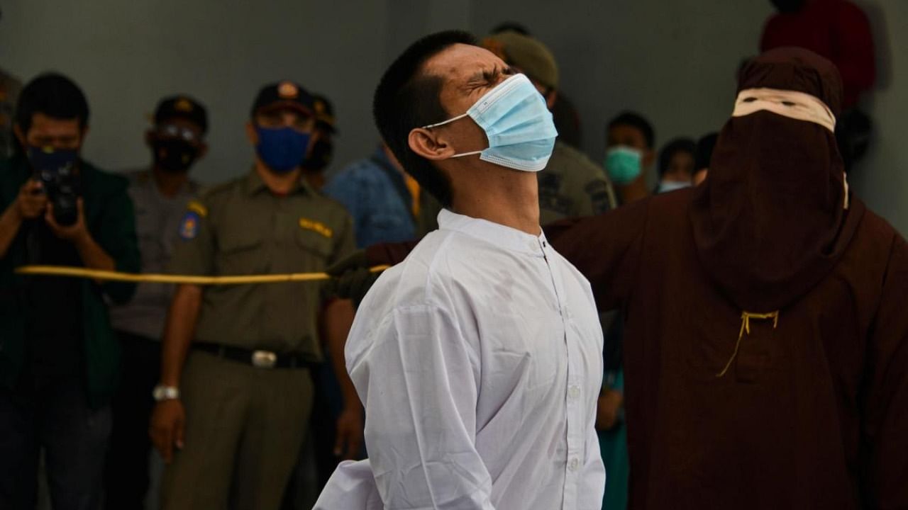 A man accused of having gay sex is publicly caned by a member of the Sharia police in Banda Aceh. Credit: AFP.