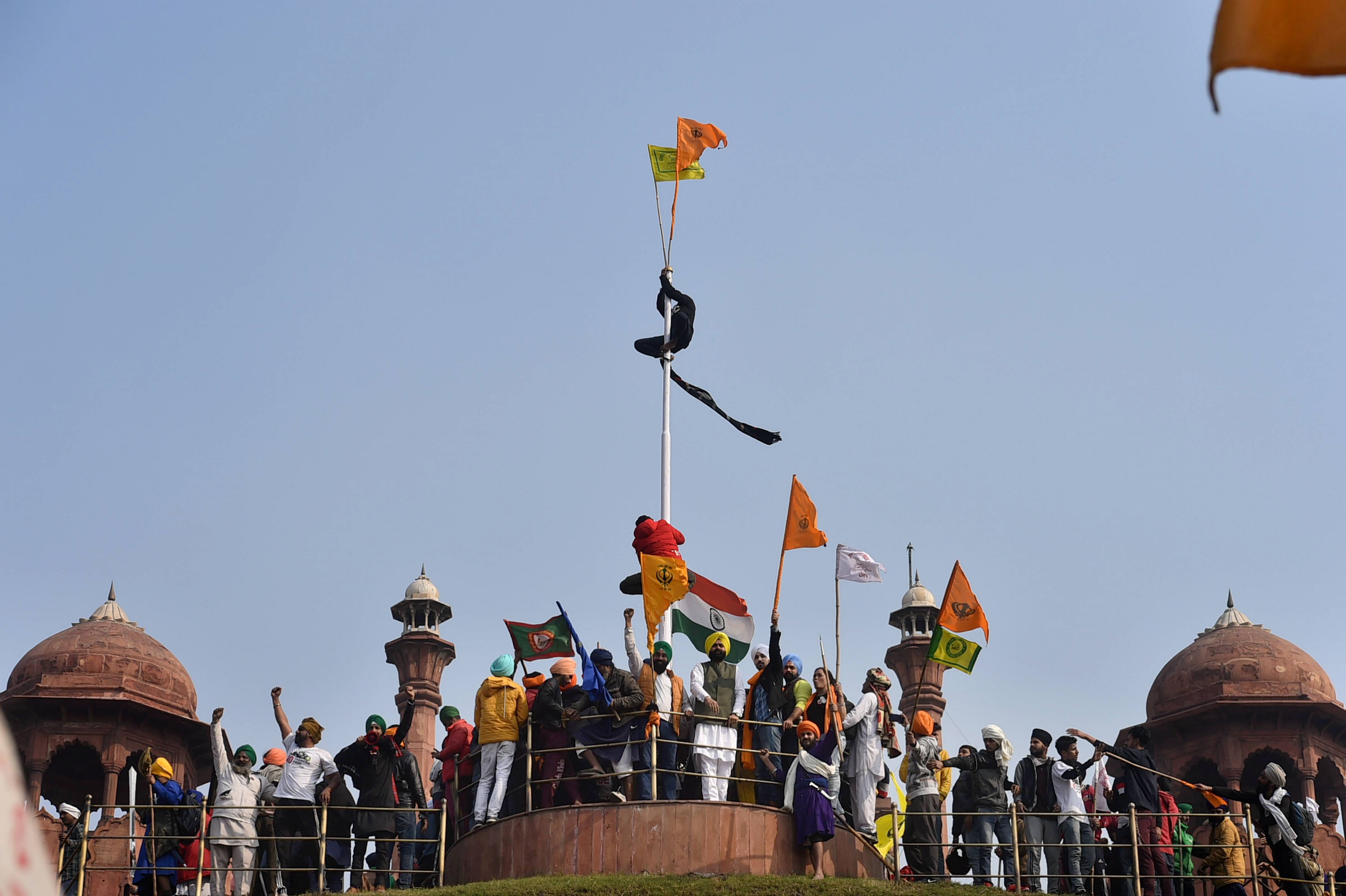 Farmers hoist flags at the Red Fort during the 'Kisan Gantantra Parade' amid the 72nd Republic Day celebrations, in New Delhi, Tuesday, Jan. 26, 2021. Credit: PTI Photo