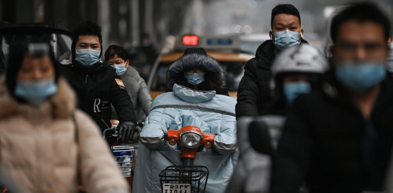 Mask-clad commuters ride past The Jade Boutique Hotel, where members of the World Health Organization (WHO) team investigating the origins of the Covid-19 coronavirus pandemic are due to complete their quarantine, in Wuhan. Credit: AFP. 