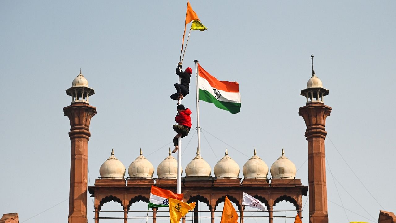 Protesters climb a flagpole at the ramparts of the Red Fort as farmers continue to demonstrate against the central government's recent agricultural reforms in New Delhi on January 26, 2021. Credit: AFP Photo