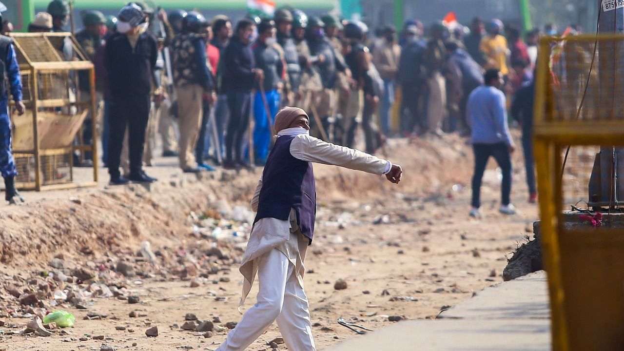 An opponent (C) throws a stone at the farmers during clashes as the farmers continue protesting against the central government's recent agricultural reforms clash at the Delhi-Haryana state border in Singh on January 29, 2021. Credit: AFP Photo