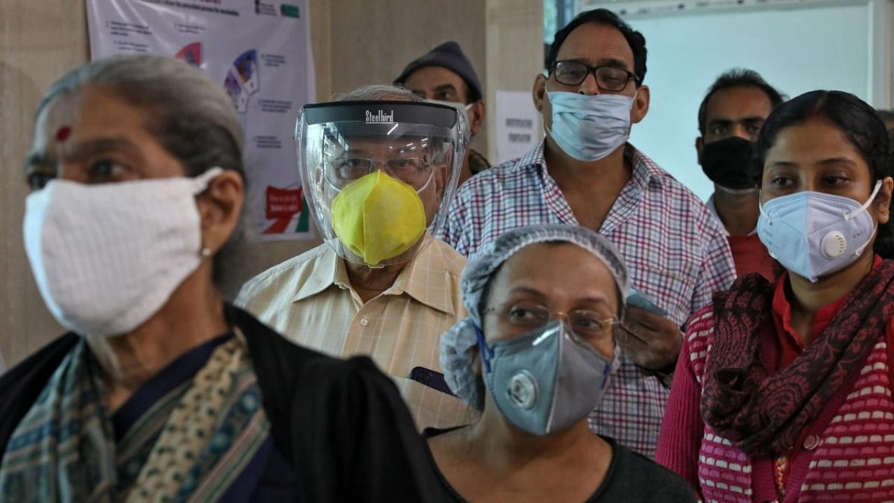 People wearing protective face masks wait to register their names for a Covid-19 vaccine at a government-run health clinic in Kolkata. Credit: Reuters.