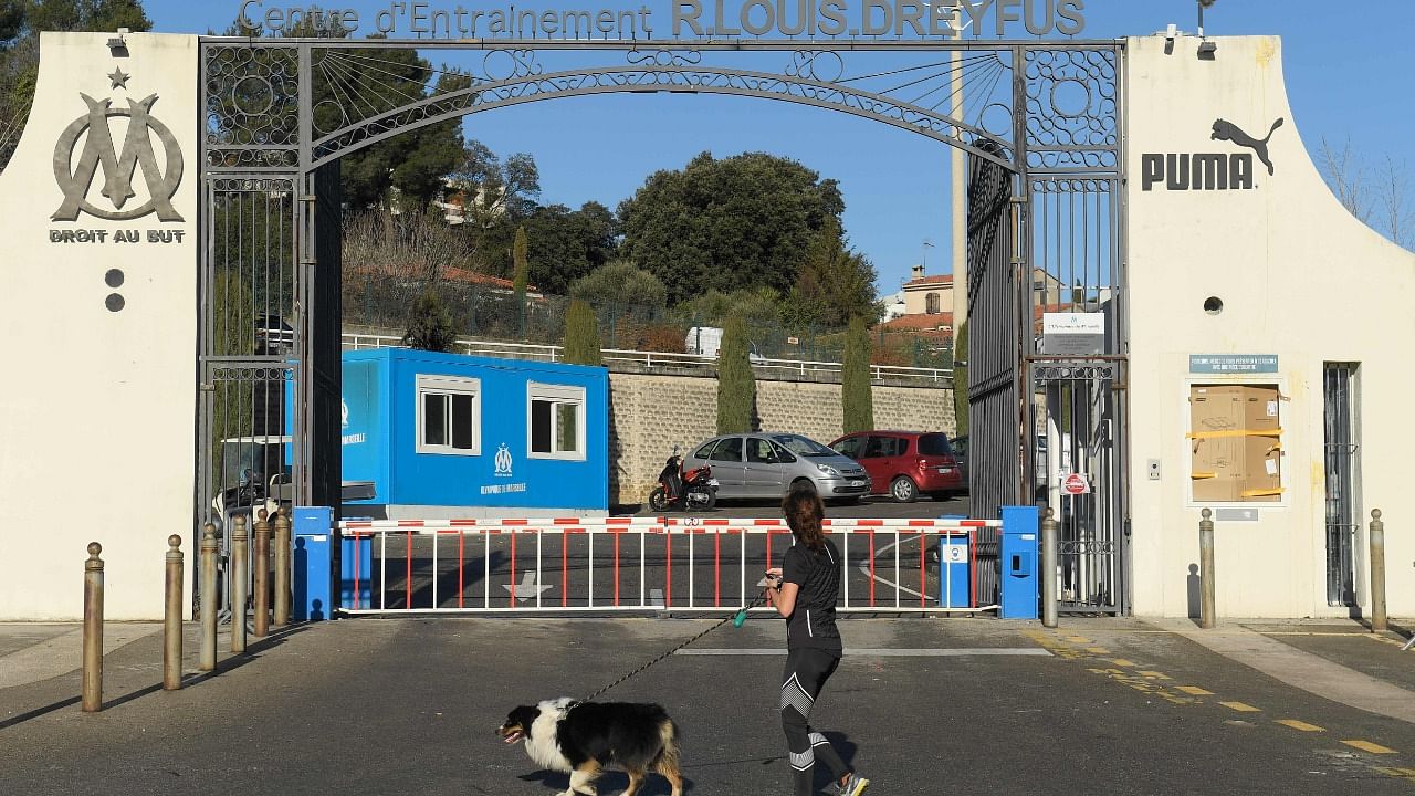 A woman walks her dog past Olympique de Marseille' Robert-Louis-Dreyfus training centre (formally known as La Commanderie) in Marseille, southeastern France, on January 31, 2021, the morning after angry fans broke in. Credit: AFP Photo