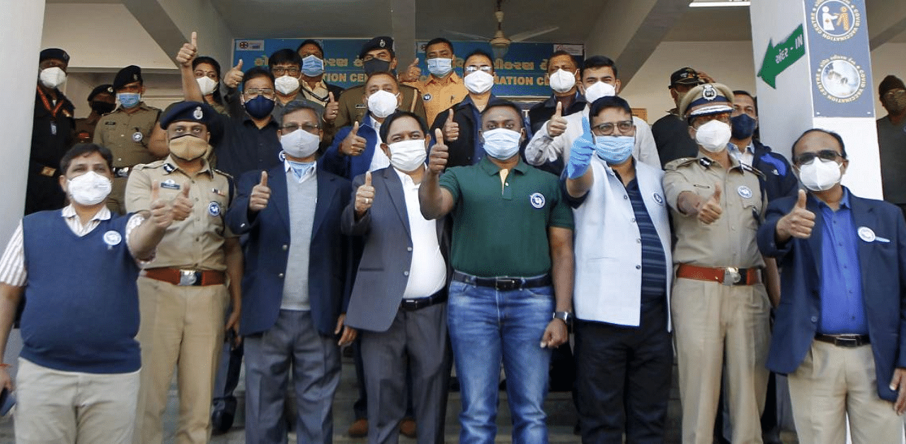  Collector Sandip J. Sagale (C) along with senior police officers poses for photographs after taking the Covishield vaccine, at Civil hospital in Ahmedabad. Credit: PTI Photo
