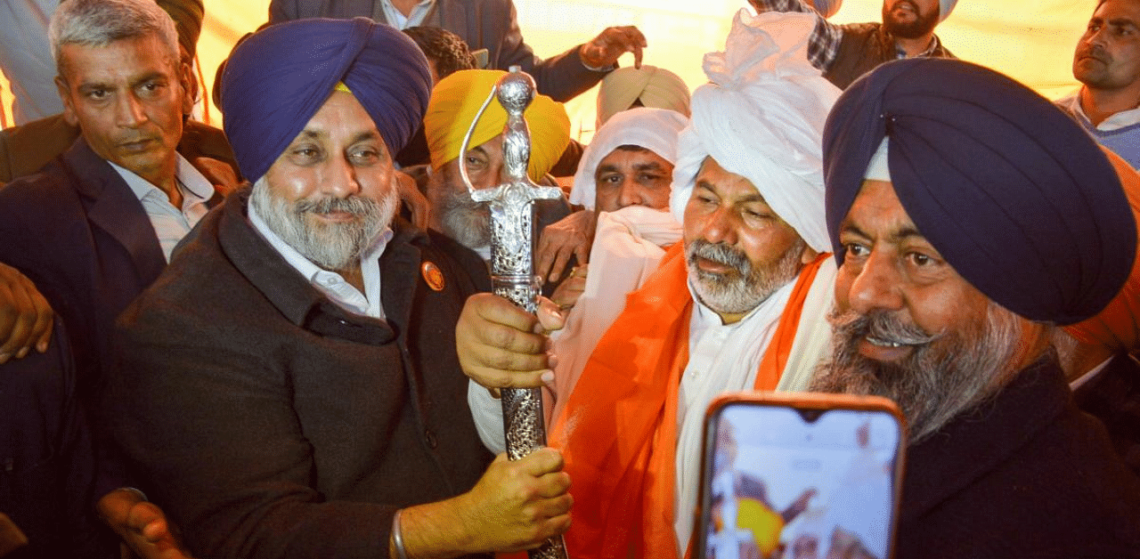 Shiromani Akali Dal (SAD) President Sukhbir Singh Badal presents a sword to Bharatiya Kisan Union (BKU) spokesperson Rakesh Tikait at Ghazipur during the ongoing farmers' protest. Credit: PTI Photo