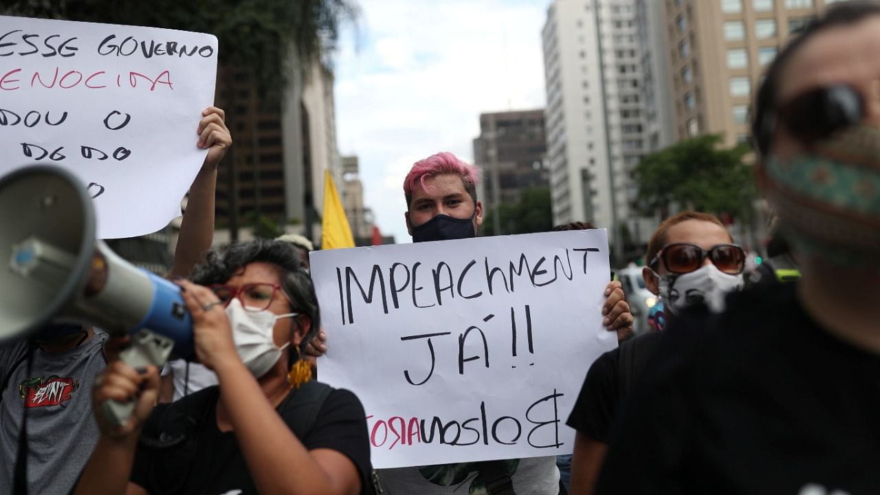 A demonstrator holds a placard reading ''Impeachment now, Bolsonaro out'' as they take part in a protest against Brazil's President Jair Bolsonaro and his handling of the coronavirus disease. Credit: Reuters Photo