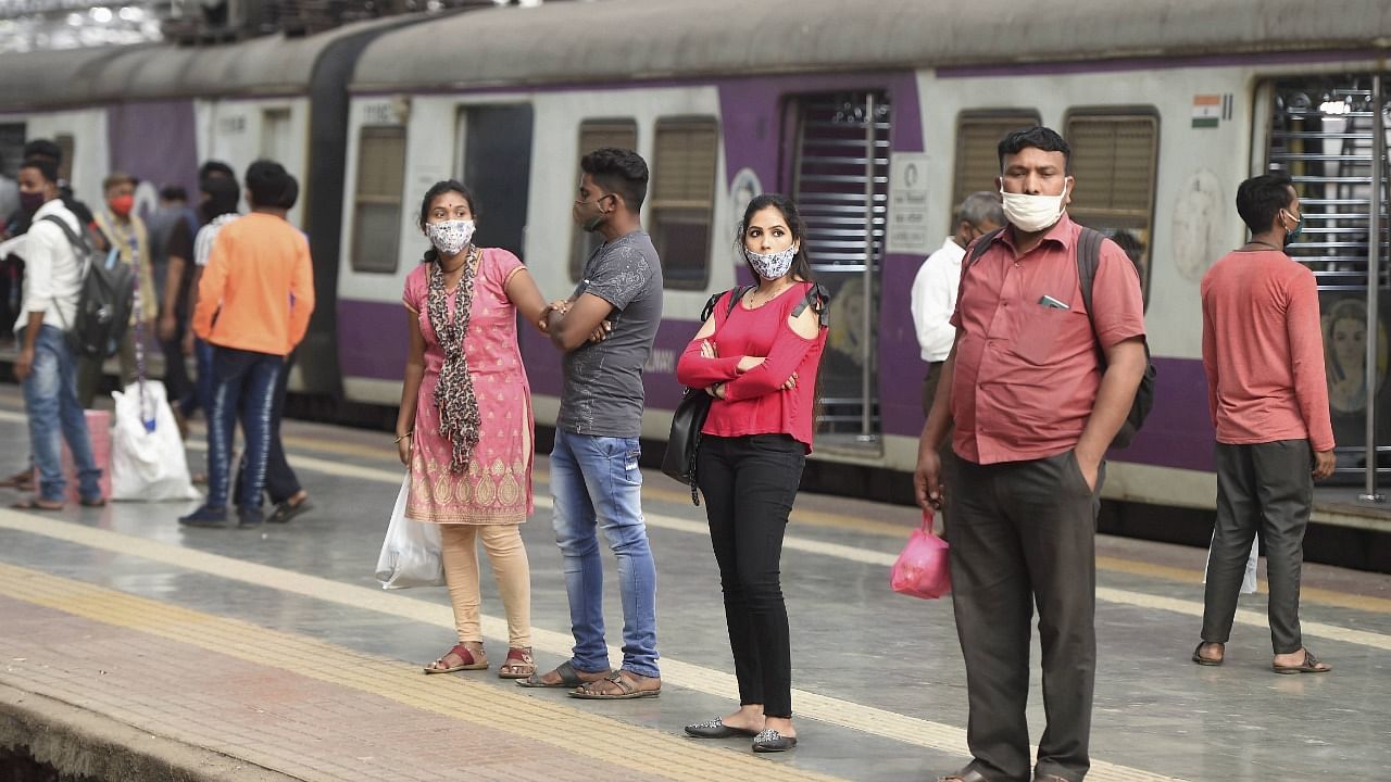 Commuters wait for a train on a railway platform as suburban train services resumed for the public after a gap of nearly ten months due to the coronavirus pandemic. Credit: PTI Photo