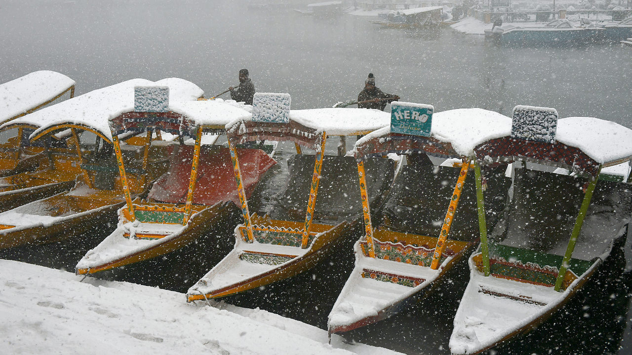Boatmen clear snow on their 'shikaras' during fresh snowfall, at Dal Lake in Srinagar. Credit: PTI Photo