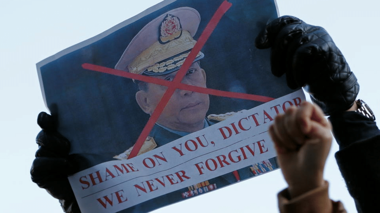 Myanmar protesters residing in Japan raise their fists and shout slogans as they show a picture of Myanmar's army chief Min Aung Hlaing with X mark during a rally against Myanmar's military. Credit: Reuters Photo