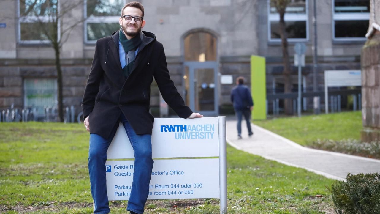 Syrian Abdul Kader Tizini who graduated with a master's degree in mechanical engineering from RWTH Aachen, sits on a sign of the university in Aachen. Credit: Reuters.