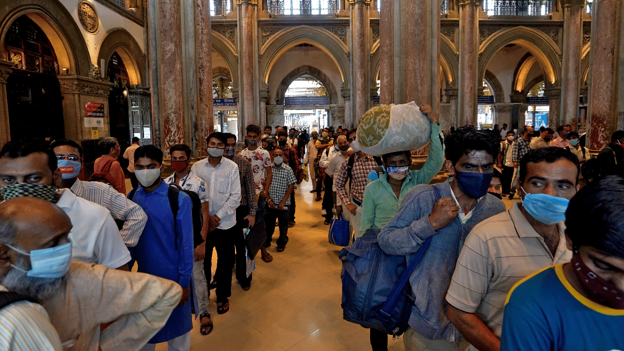 People wearing protective face masks wait in queues to buy train tickets at the CSMT railway station in Mumbai. Credit: Reuters Photo