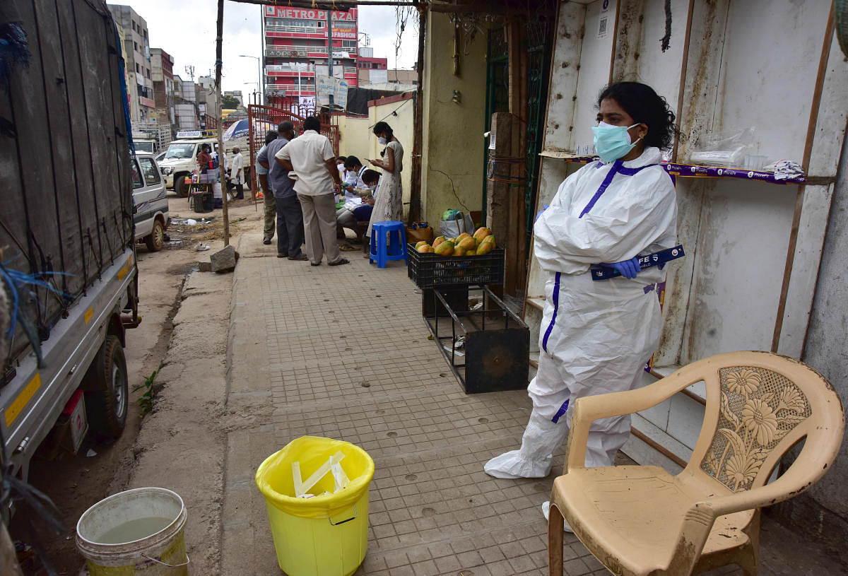 A healthcare worker waits for people to test them for Covid-19 on a footpath at Chickpet, Bengaluru's traditional business hub. DH PHOTO/IRSHAD MAHAMMAD