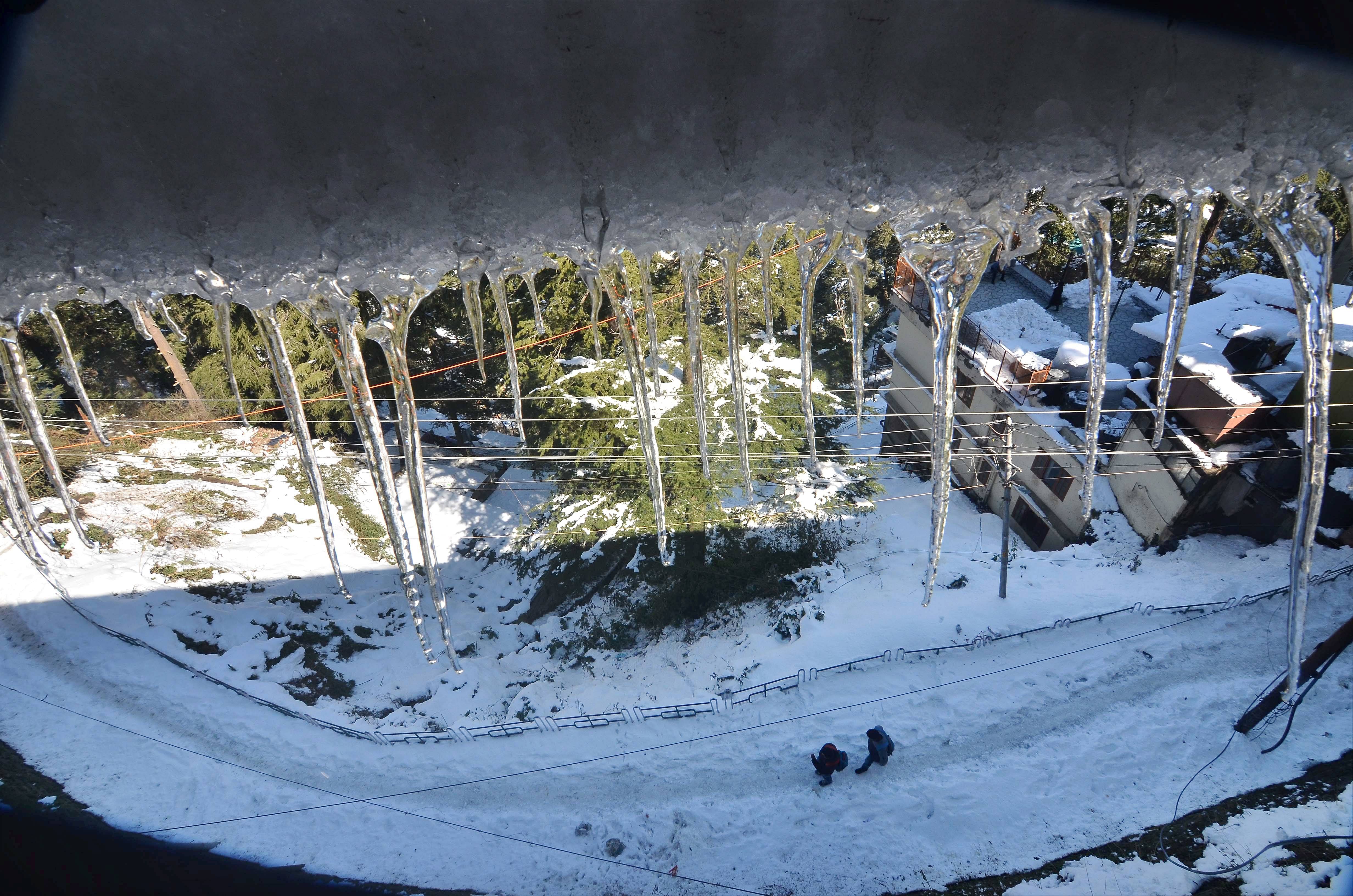 Icicles hang from the roof of a house in the backdrop of a neighbourhood covered in snow, in Shimla, Saturday, Feb. 6, 2021. Credit: PTI Photo