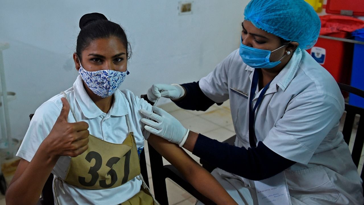 A health worker inoculates a Gujarat Police's Lok Rakshak Dal (LRD) personnel with a Covid-19 coronavirus vaccine at a civil hospital in Ahmedabad. Credit: AFP File Photo.