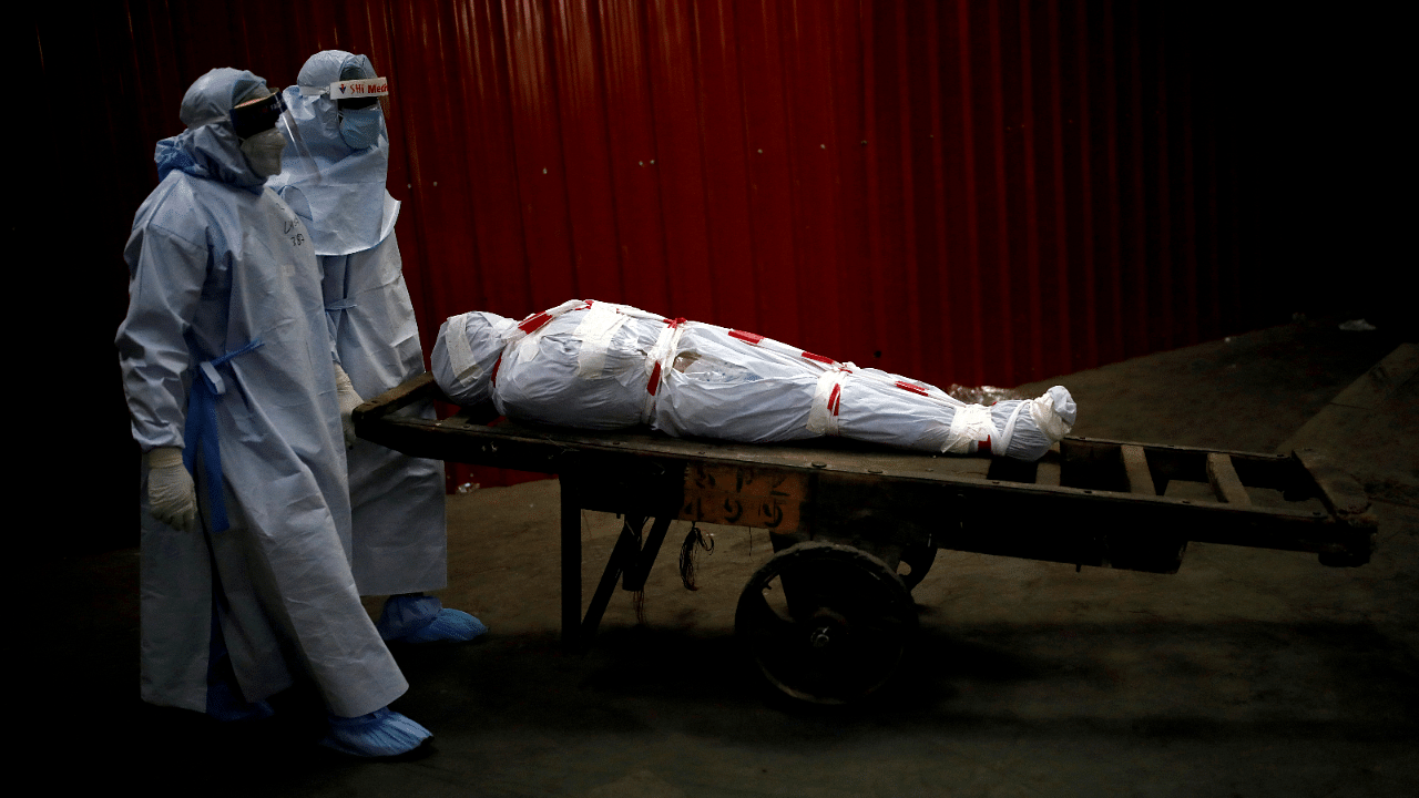 Health workers carry the body of a man who died due to the coronavirus disease for his cremation at a crematorium. Credit: Reuters Photo