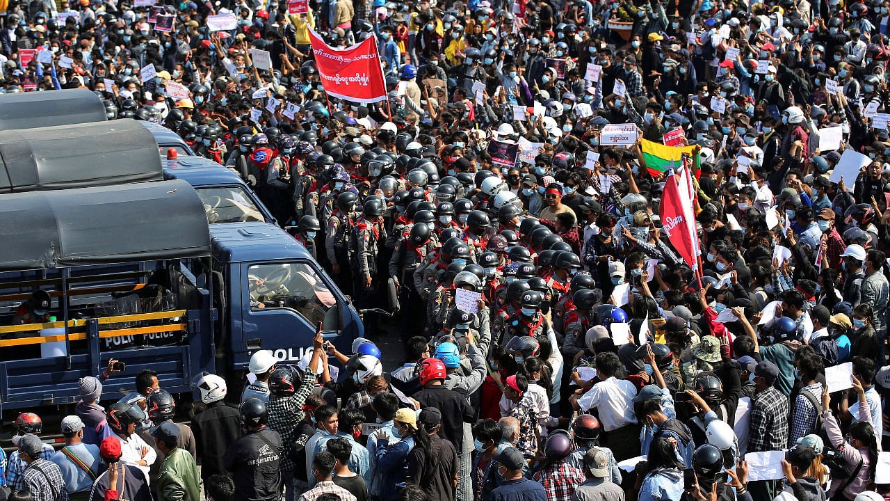 Police stand guard by their vehicles as protesters rally against the military coup and to demand the release of elected leader Aung San Suu Kyi. Credit: Reuters Photo