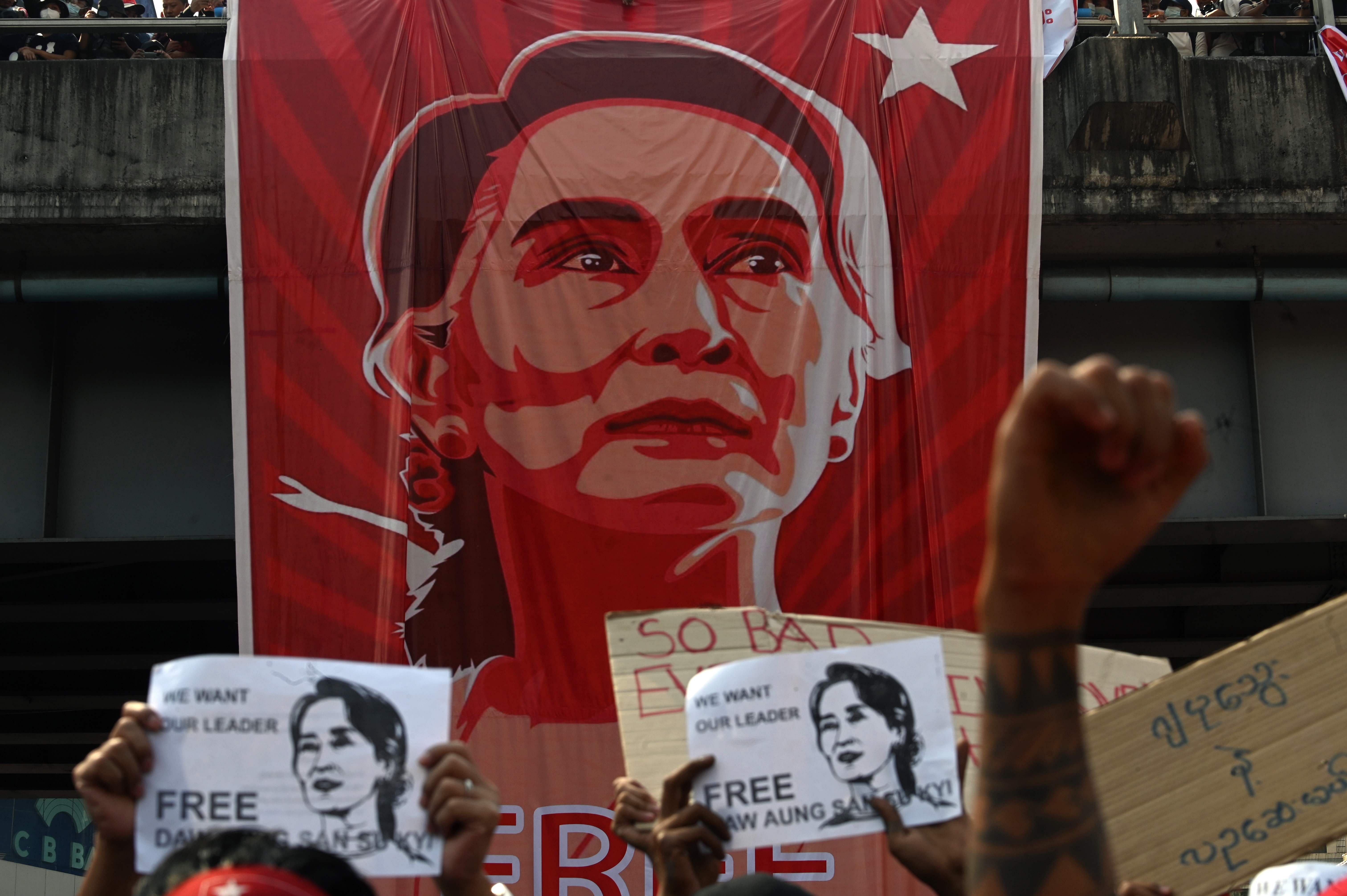 Protesters stand in front of a huge banner of detained Myanmar leader Aung San Suu Kyi as they part in a demonstration against the military coup in Yangon on February 9, 2021. Credit: AFP Photo