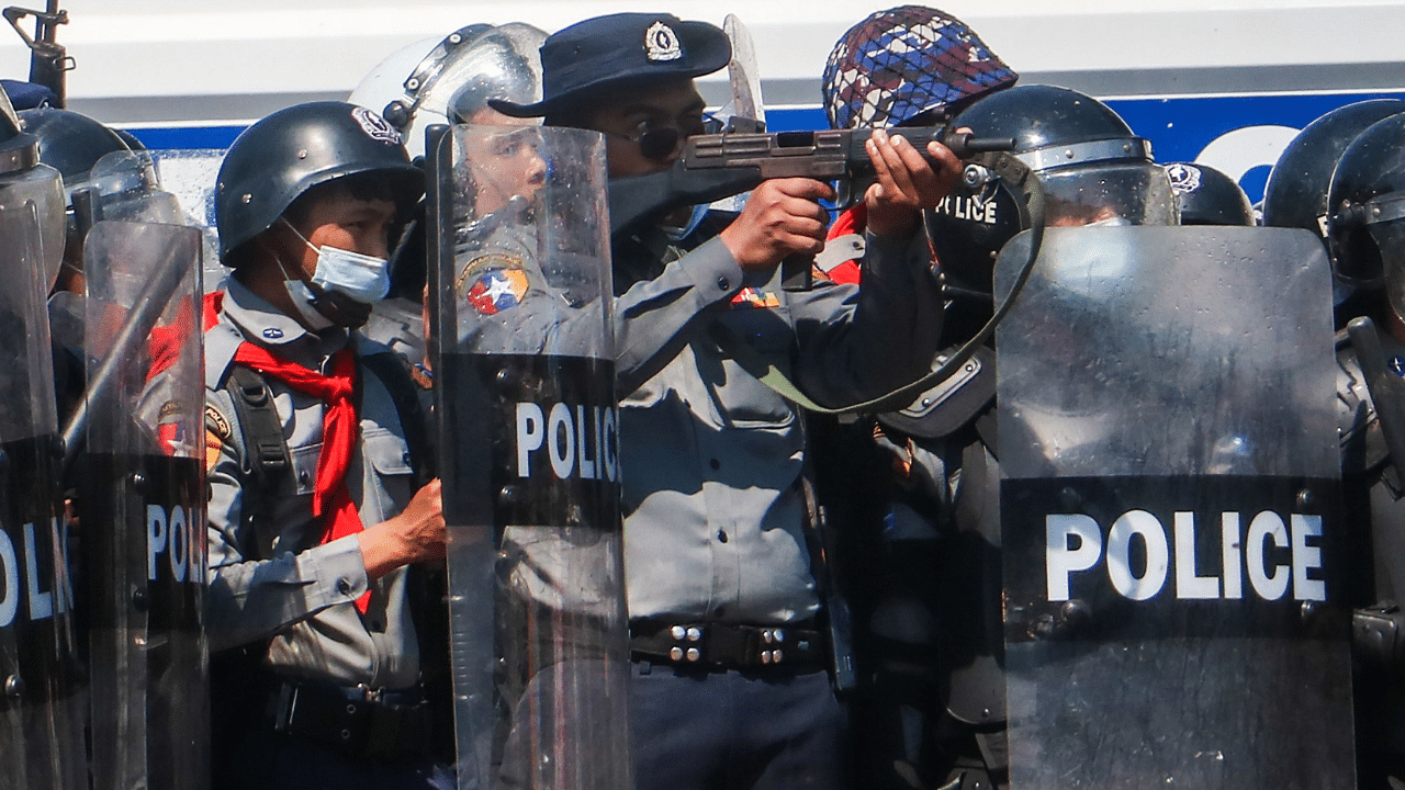 A police officer (C) aims a gun during clashes with protesters taking part in a demonstration against the military coup in Nay Pyi Taw. Credit: AFP Photo