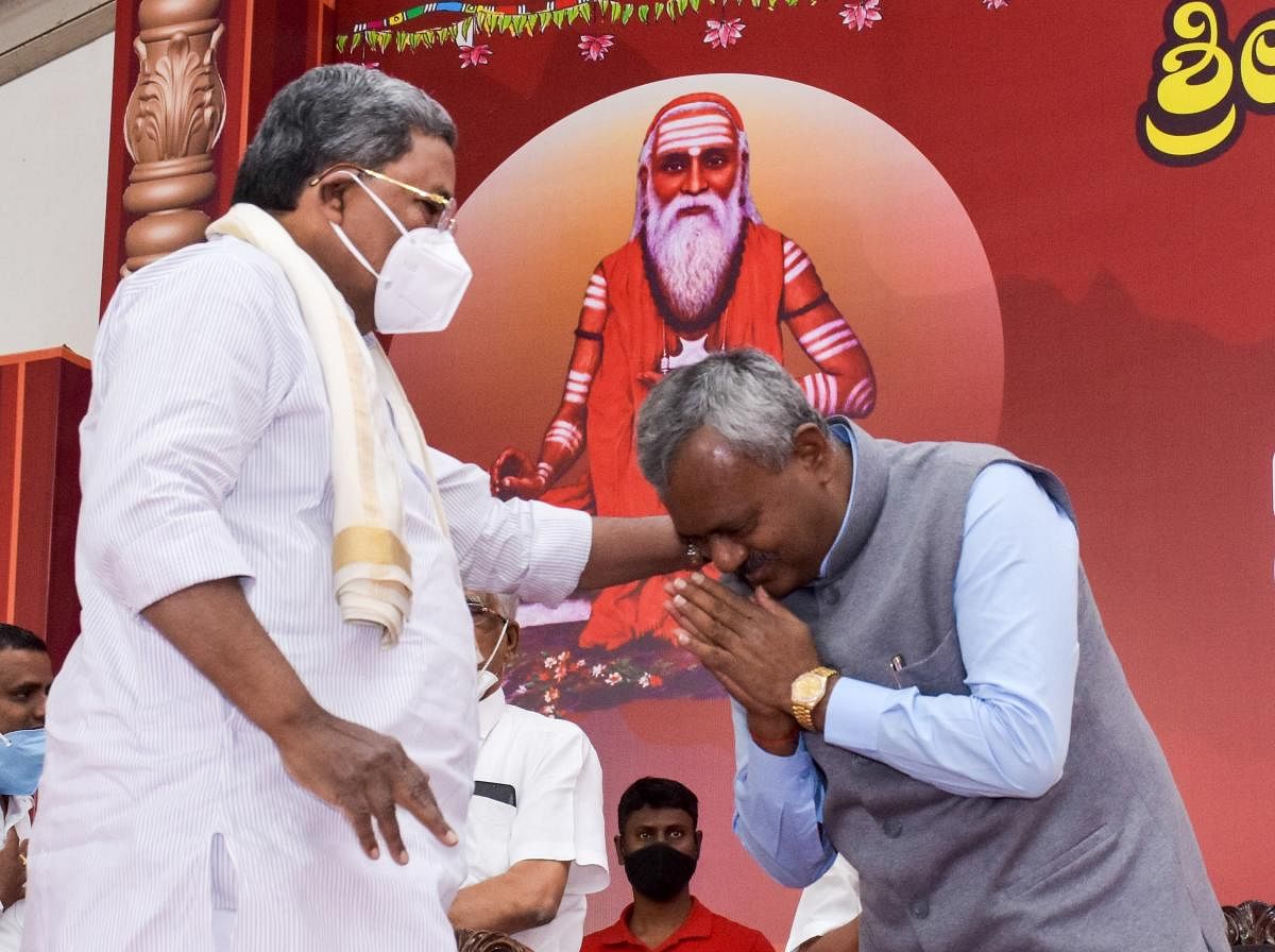 District In-charge Minister S T Somasekhar bows before his former mentor and Leader of Opposition party Siddaramaiah, during the 95th monthly ‘mass marriage’, organised by Jagadguru Sri Veerasimhasana Mahasamsthana Mutt, Suttur, Nanjangud taluk on Tuesday. DH PHOTO