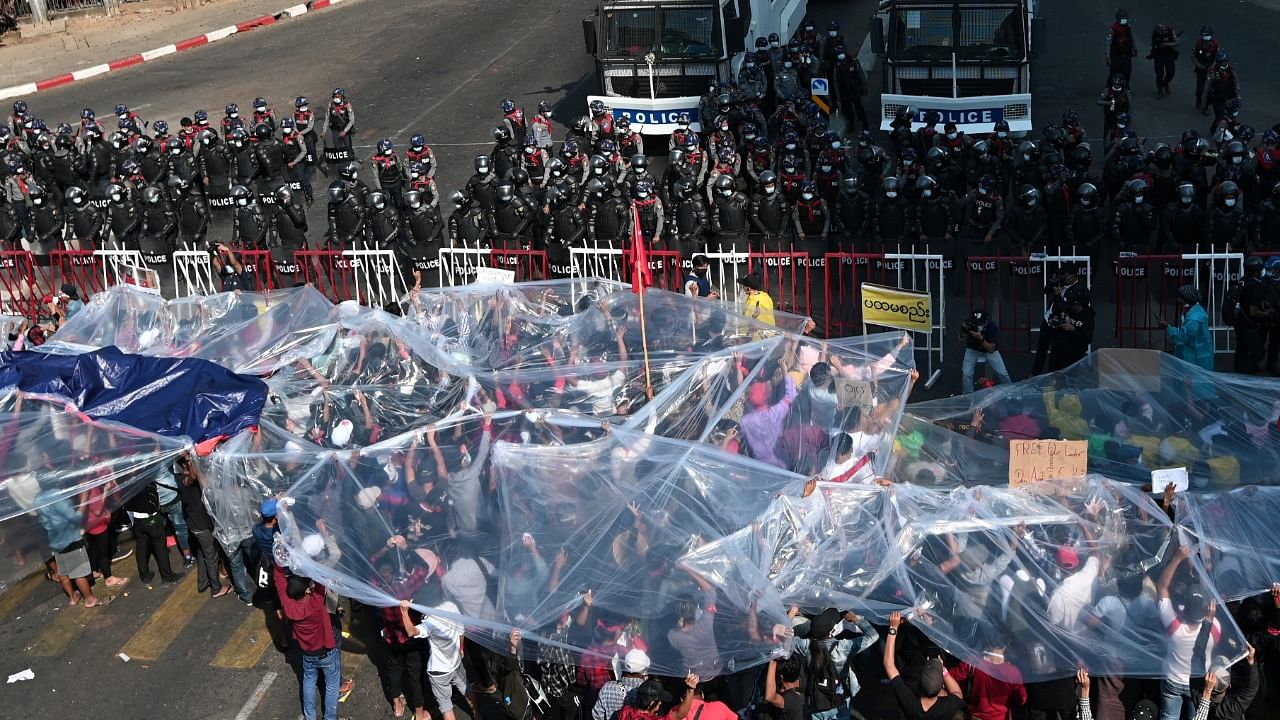 People cover with plastic in case of a water canon during a rally against the military coup and to demand the release of elected leader Aung San Suu Kyi, in Yangon, Myanmar, February 9, 2021. Credit: Reuters Photo