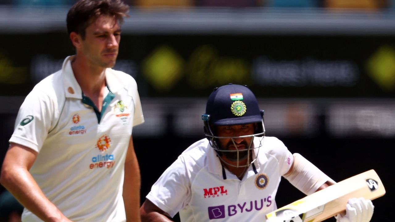 Cheteshwar Pujara (R) runs between the wickets as Australia's paceman Pat Cummins walks back to his bowling marks on day five of the fourth cricket Test match between Australia and India at The Gabba in Brisbane on January 19, 2021. Credit: AFP Photo