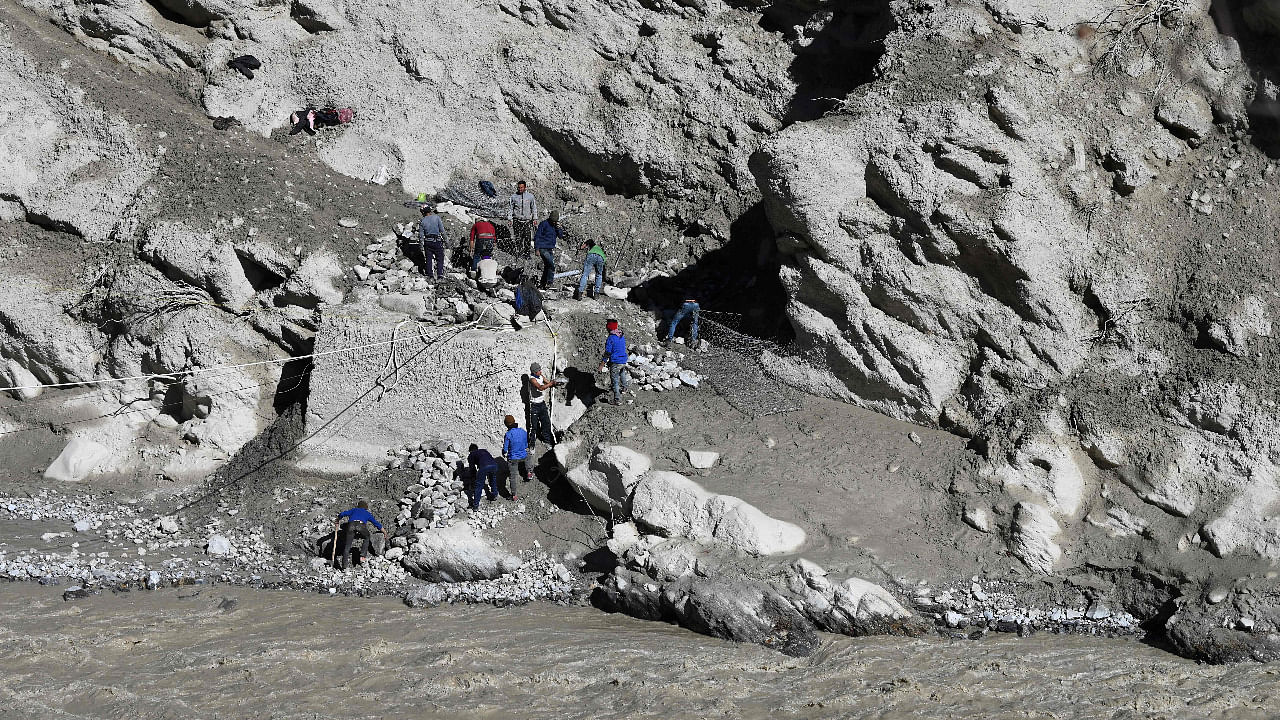 Workers set-up a line to cross the Dauliganga river near Tapovan tunnel in Chamoli district. Credit: AFP Photo