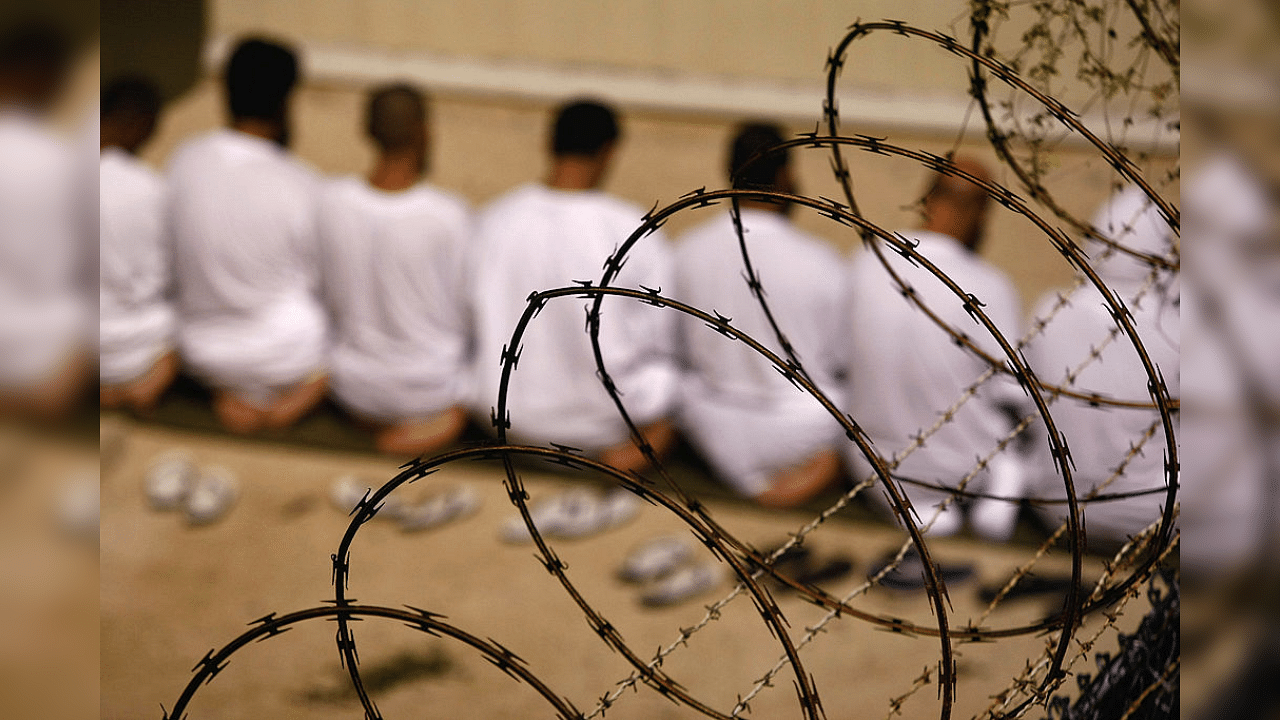 A group of detainees kneels during an early morning Islamic prayer in their camp at the U.S. military prison for "enemy combatants" on October 28, 2009 in Guantanamo Bay, Cuba. Credit: Getty Images