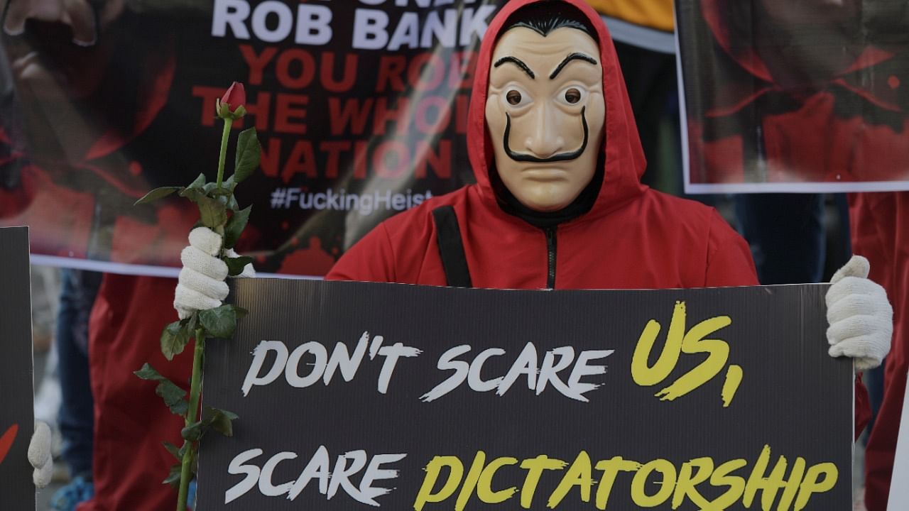 A demonstrator wearing a costume from ''La Casa de Papel (Money Heist)'' holds a sign during a protest against the military coup in Yangon, Myanmar, February 13, 2021. Credit: Reuters Photo