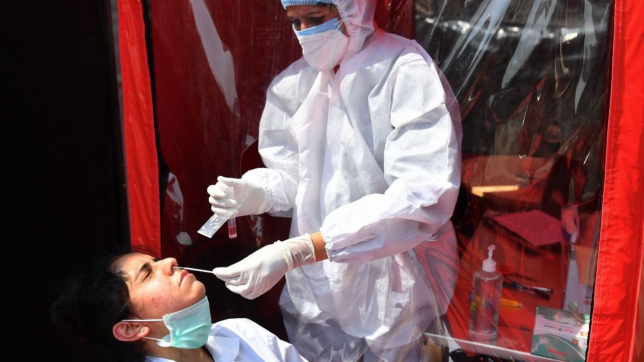 A health worker takes swab sample of a colleague at a portable cabin of a mobile laboratory for conducting RT-PCR Covid-19 coronavirus tests in Mumbai on February 11, 2021. Credit: AFP Photo