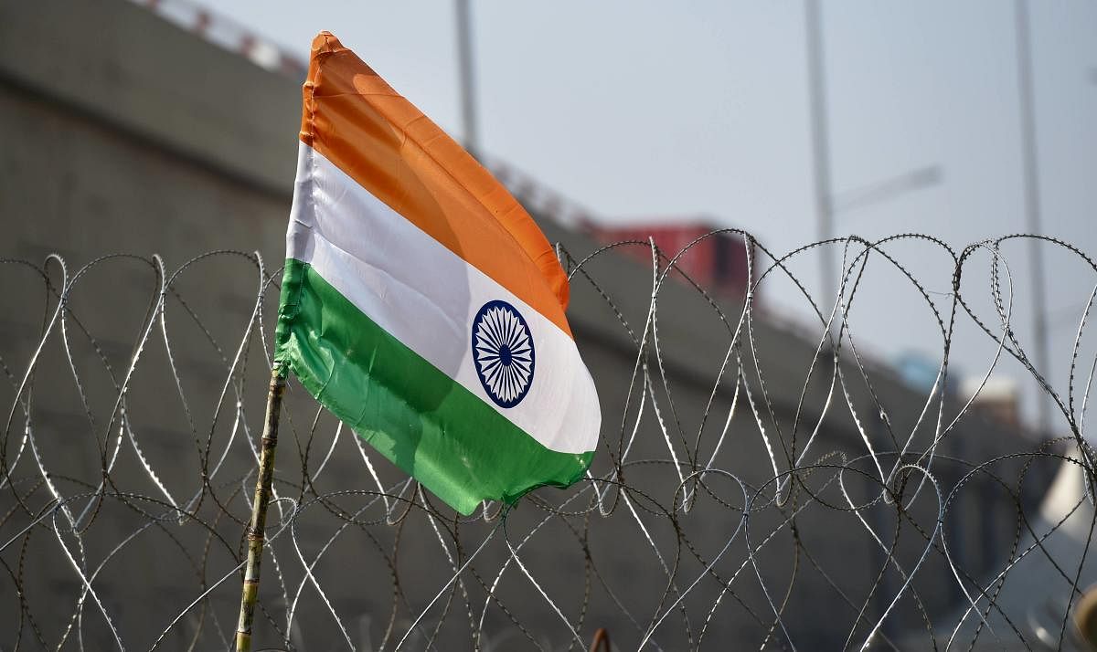 The Indian national flag is seen hoisted next to barbed wires, used as barricades ahead of the proposed 'chakka jam' by farmers, during their ongoing agitation against Centre's farm reform laws, at Ghazipur border in New Delhi, Saturday, Feb. 6, 2021. Credit: PTI Photo