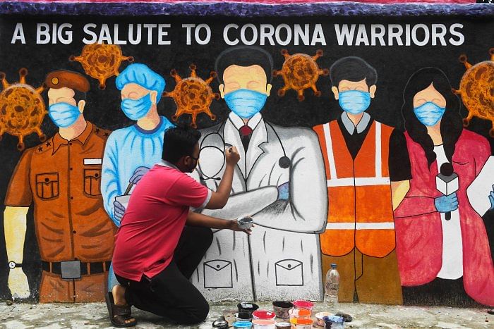 An artist gives finishing touches to a mural depicting frontline workers during a day-long complete lockdown imposed by the state government against the surge in Covid-19 coronavirus cases in Kolkata. Representative image/Credit: AFP Photo