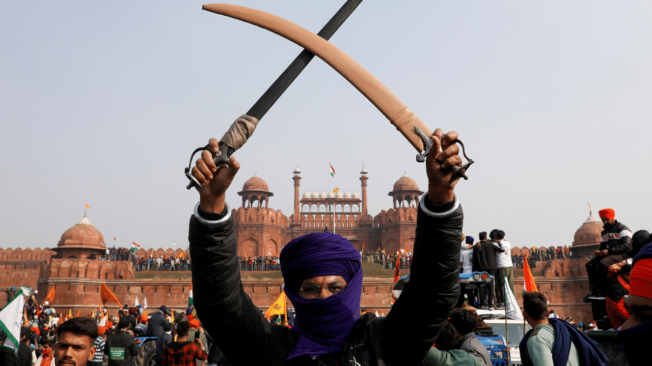 A farmer holds swords during a protest against farm laws introduced by the government, at the historic Red Fort in Delhi. Credit: Reuters Photo