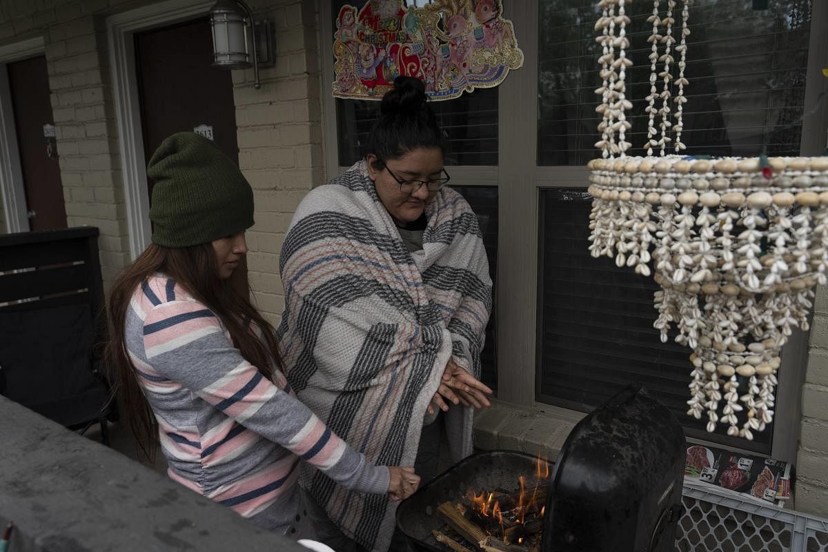 Karla Perez and Esperanza Gonzalez warm up by a barbecue grill during power outage caused by the winter storm on February 16, 2021 in Houston, Texas. Credit: AFP photo. 