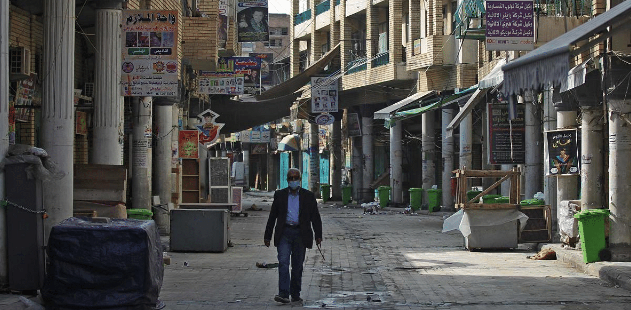 An Iraqi man walks past closed shops in Baghdad on February 19, 2021, as authorities re-imposed partial lockdown measures until early March after detecting a new strain of the coronavirus. Credit: AFP Photo