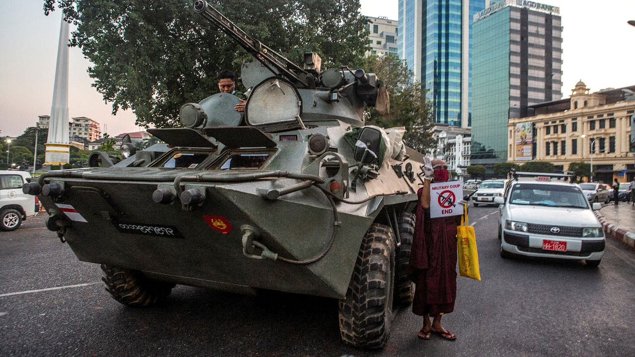 A Buddhist monk holding a sign stands next to an armoured vehicle during a protest against the military coup, in Yangon. Credit: Reuters Photo